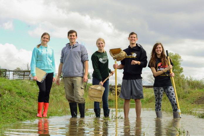 HU students and professor picking up trash from a creek. 