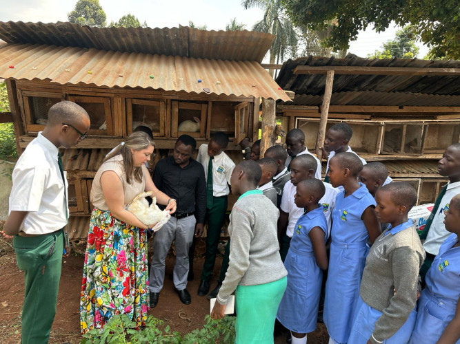 A woman holding a rabbit to teach a village about livestock and agriculture.