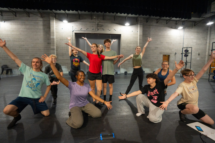 A group of student pose on the theatrical stage.