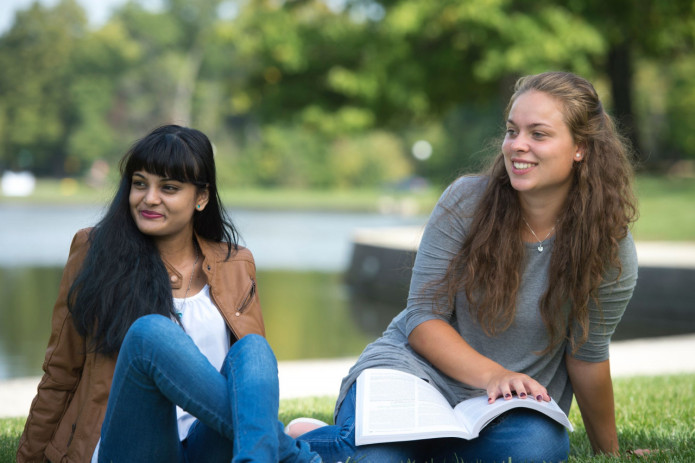 Two HU students doing homework by the lake on campus. 