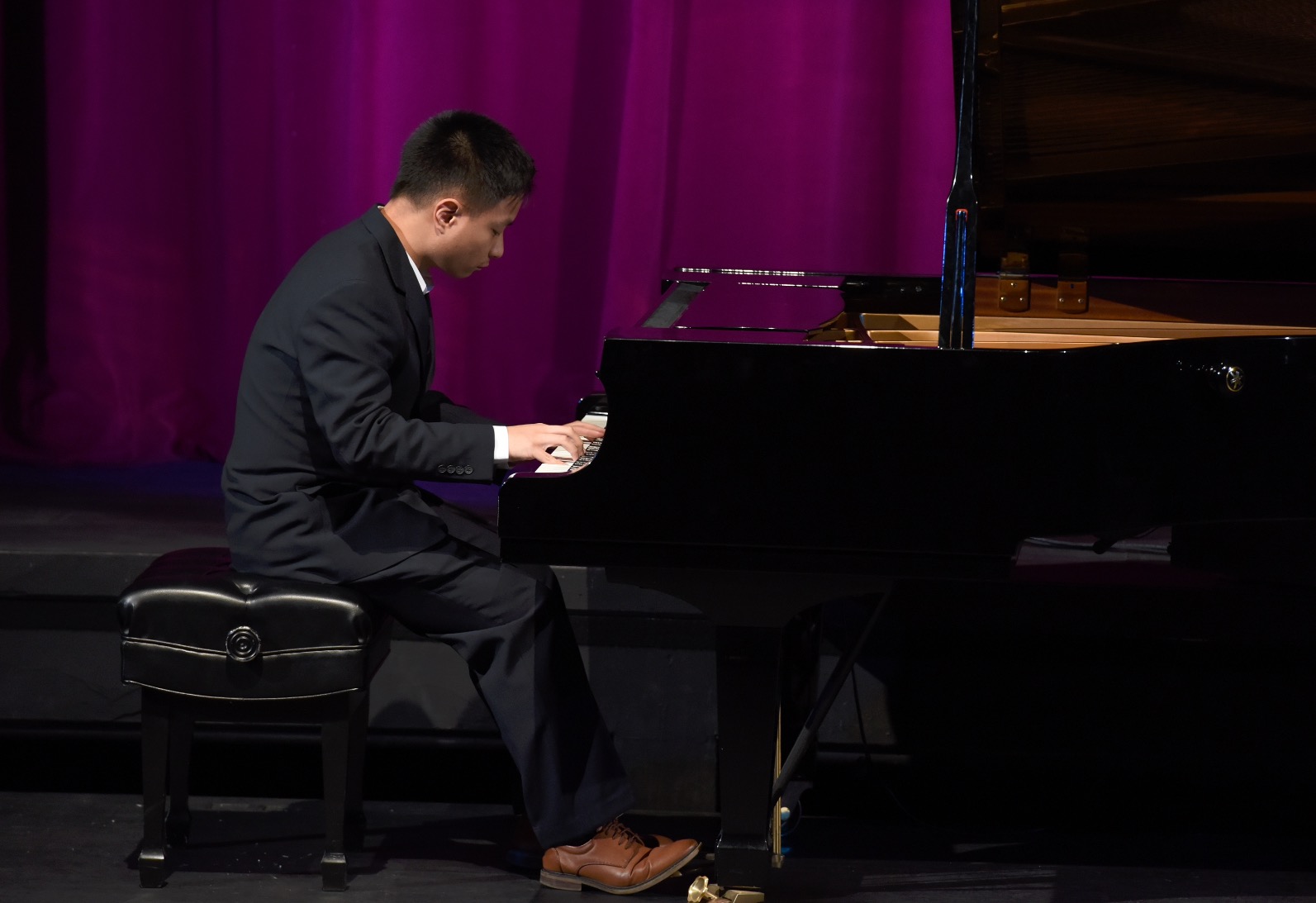 A student plays a piano in a performance setting.